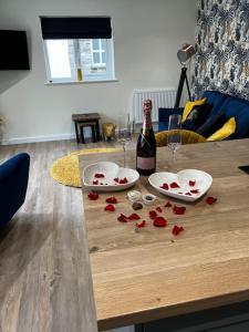 阿尔弗斯顿Ulverston stunning 1 bedroom apartment的一张桌子上放着一瓶葡萄酒和红玫瑰