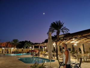 杰里科巴巴尔沙姆度假酒店的一位晚上站在游泳池旁的人