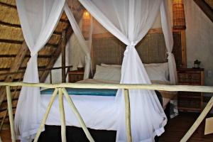 GemsbokfonteinHot Spring bungalow in Limpopo的卧室配有带白色窗帘的天蓬床