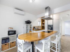 比利切Modern holiday home in Bilice with private pool的厨房配有木桌和白色凳子