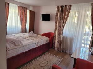 锡纳亚图伊旅馆的一间卧室配有床、电视和窗帘