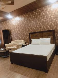 拉合尔Royal Fort Executive Hotel Gulberg的一间卧室配有一张床、一把椅子和一张沙发