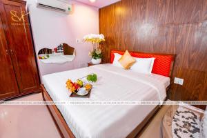 胡志明市Bonka Hotel Luxury Quận 5 HCM的一间卧室,配有一张带鲜花托盘的床