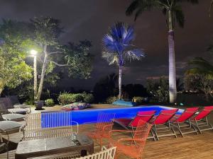 Le Bois de NèflesVilla Jujubes的游泳池在晚上设有椅子和棕榈树