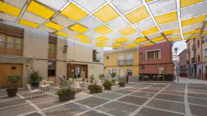 布利亚斯Casa rural Plaza Vieja en Bullas的庭院设有桌椅和黄色及白色的天花板。