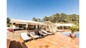 圣塔格鲁迪斯Attractive Ibiza Villa Can Tierra 6 Bedrooms Phenomenal Country and Mountain Views Santa Gertrudis的游泳池旁带椅子和遮阳伞的天井