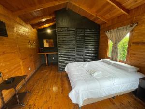 迦太基Grandpas Hotel & Restaurante的木制客房内的一间卧室配有一张白色大床