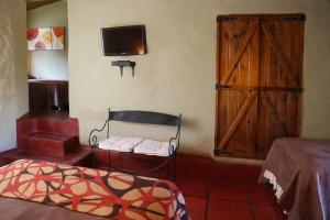 塔菲德尔瓦勒波萨达拉瓜达卢佩酒店的卧室配有一张床,墙上配有电视。
