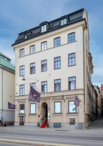 斯德哥尔摩Hotel Gamla Stan, BW Signature Collection的前面有紫色旗帜的大型白色建筑