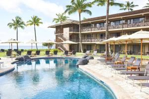 科洛阿Koa Kea Resort on Poipu Beach的一个带游泳池、椅子和遮阳伞的度假村