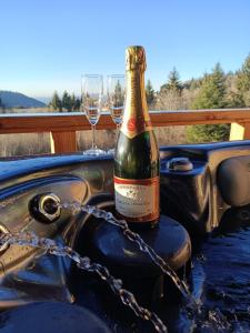 BelfahyChalet neuf avec jacuzzi privé, vue imprenable sur Massif des Vosges的一张桌子上摆放着一瓶香槟,配上两杯酒杯