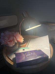 彭里斯Honeysuckle Cottage & Whinfell Studio的一张桌子,上面有台灯,一本书和一朵花