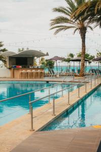 波拉马尔Tibisay Hotel Boutique Margarita的一座棕榈树和遮阳伞的游泳池