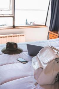 圣卡洛斯-德巴里洛切Tangoinn Hostel Downtown的床上的帽子和钱包,带笔记本电脑