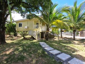 罗阿坦Single-Family Home With Gated Tropical Yard的黄色房子,设有门廊和棕榈树