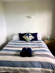 阿希帕拉90 Mile Paradise Ahipara的一张带蓝色和白色条纹床单和枕头的床
