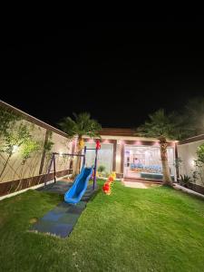 哈伊勒شاليه فاملي دي family day的夜间在院子里带滑梯的游乐场