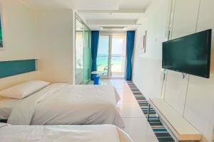 济州市Hamdeok Beach Stay Jeju的酒店客房设有两张床和一台平面电视。