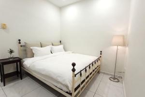 新山The Penggawa Homestay - 3 comfortable bedrooms的卧室配有一张带灯的白色大床