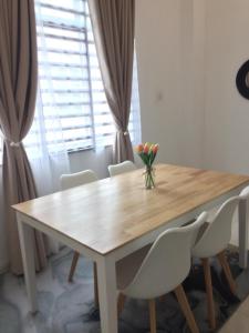 关丹Rooma Singgah Homestay @ Cherating的一张带白色椅子的木桌和花瓶