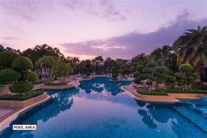 北芭堤雅泰花园度假酒店的树木和日落的度假村的游泳池