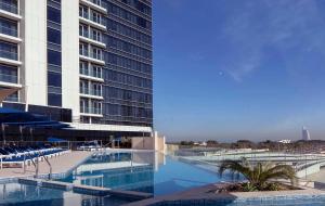 迪拜ON OFF HH-AVANI HOTEL-3BR -Full Palm View的一座高楼旁边的大型游泳池