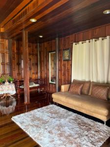 Ban Chak PhaiTraditional Thai house บ้านเรือนไทย ใกล้หาดระยอง的带沙发和木墙的客厅