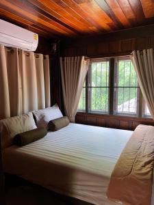 Ban Chak PhaiTraditional Thai house บ้านเรือนไทย ใกล้หาดระยอง的一间卧室设有一张大床和两个窗户