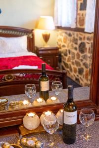 帕雷斯阿吉萨那Palaios Agios Athanasios Luxury Μaisonette的镜子前的桌子上放着两瓶葡萄酒和眼镜