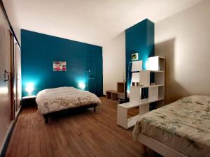 圣瑞尼安Chambres d'hôtes La Maison Blanche的一间卧室设有两张床和蓝色的墙壁