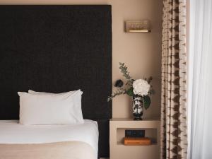 巴黎Le Rayz Vendome的一间卧室配有床和花瓶