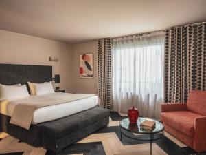 巴黎Le Rayz Vendome的酒店客房,配有一张床和一张红色椅子