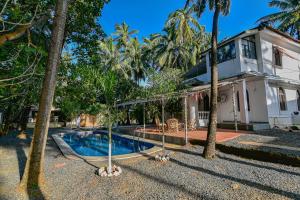 卡兰古特GR Stays WHITE HOUSE 4bhk Private Pool Villa in Calangute的一座带游泳池和棕榈树的房子