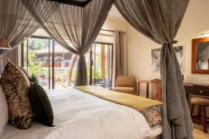 维多利亚瀑布Shongwe Oasis的一间卧室配有一张带窗帘的床和一张书桌
