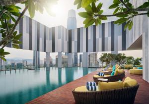吉隆坡Pan Pacific Serviced Suites Kuala Lumpur的酒店带椅子的游泳池,享有城市美景