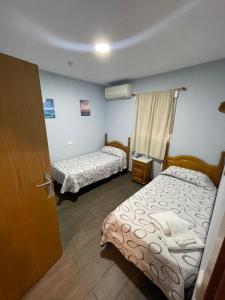 赫塔费Hostal Tres Hermanos的小房间设有两张床和一扇门