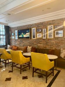 开普敦Taj HotelApart, Taj Hotel Cape Town的一间设有黄色桌椅的餐厅,以及砖墙