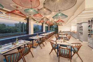 达兰萨拉INFINITEA CENTRIC DHARAMSHALA的用餐室配有桌椅和大窗户