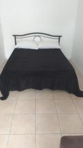 讷莱米讷Résidence Les Hauts de France的一张黑色床,铺在瓷砖地板上,配有黑色毯子