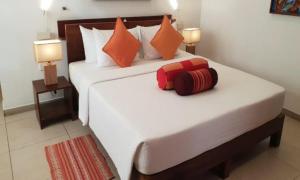 乌纳瓦图纳Rockside Cabanas Hotel的卧室配有带橙色枕头的大型白色床