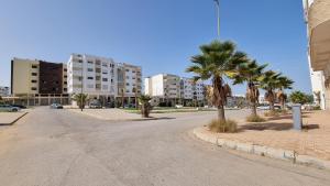 特马拉My Cosy Place Rabat - Cosy Home Wifak Temara的一条棕榈树和建筑的空街