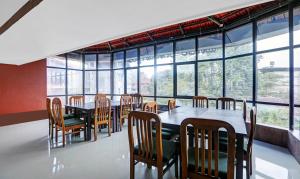 马迪凯里Itsy By Treebo - Regalia Grand 500 Mtrs From Madikeri Fort的用餐室设有桌椅和窗户。