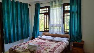 PemayangtseHotel Himsagar的一间卧室配有蓝色窗帘和一张带两个窗户的床。
