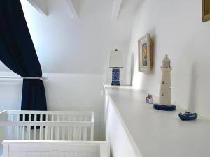 巴拉胡利什The Bothy of Ballachulish House的一间白色的房间,配有一张婴儿床,墙上设有一座灯塔