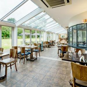 莱德沙姆克拉克斯顿伍德麦克唐纳德酒店&Spa的用餐室设有桌椅和窗户。