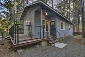 Secluded Butte Meadows Cabin with Deck and Grill!的树林里有一个大门廊的小房子