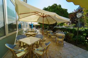 里米尼Dasamo Hotel - Dada Hotels的室外咖啡厅配有桌椅和遮阳伞