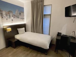 梅赫伦3 Paardekens - City Centre Hotel的一间卧室配有一张床、一个窗口和一张书桌