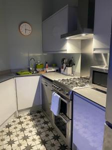 利物浦Airy Apartment Sefton Park的厨房配有炉灶和墙上的时钟