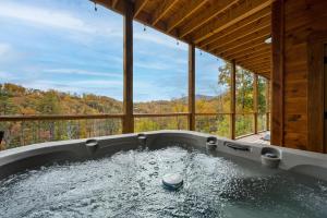 加特林堡The Overlook - '21 Cabin - Gorgeous Unobstructed Views - Fire Pit Table - GameRm - HotTub - Xbox - Lots of Bears的享有树林景色的按摩浴缸